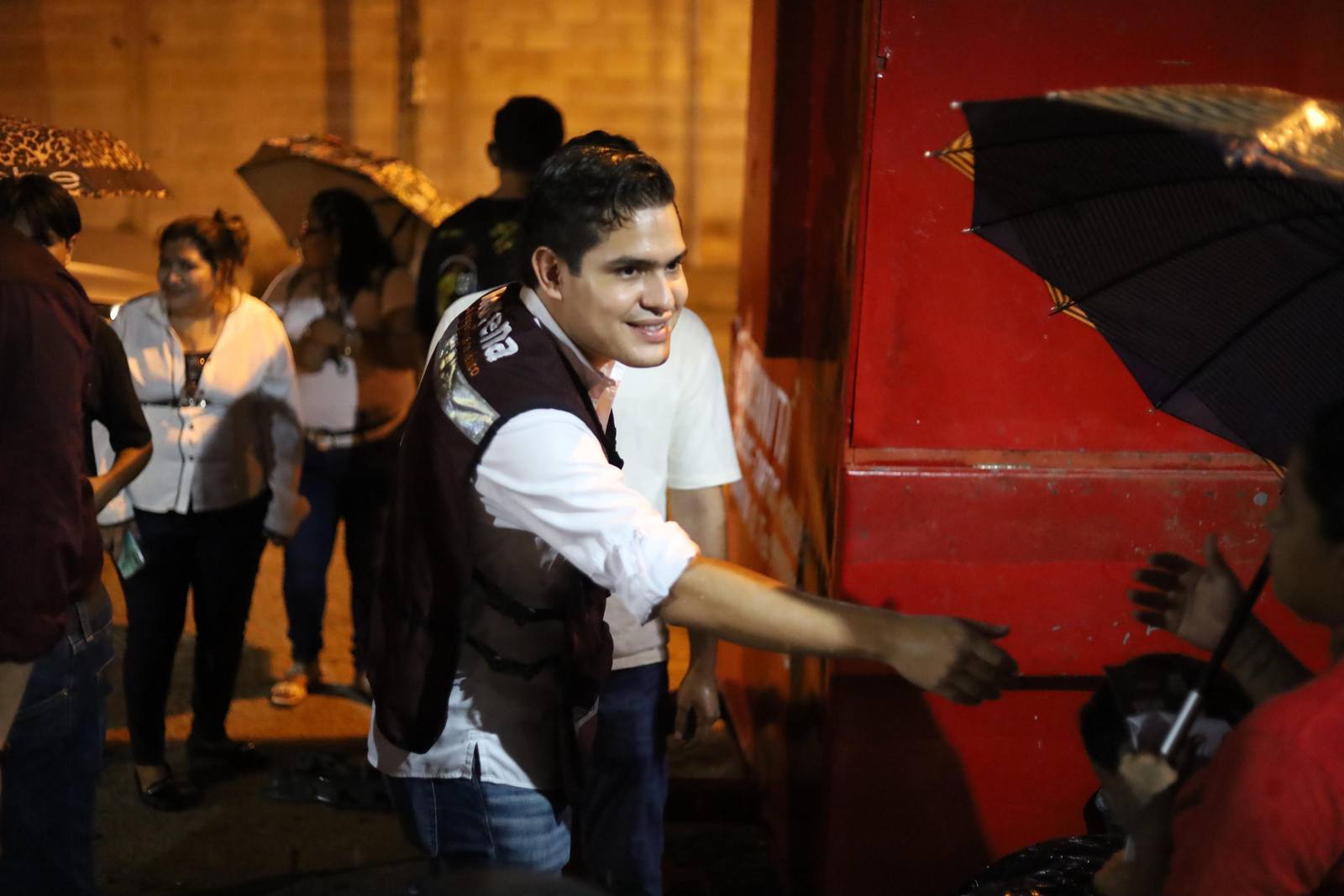 Diego Carrera saludando a vecinos en un evento de noche